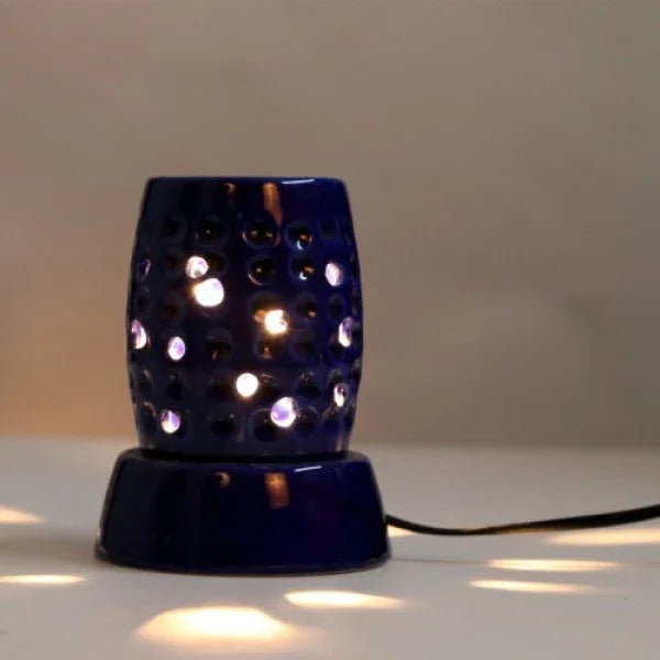 Electric blue ceramic aroma oil burner with perforated design, powered on a white surface