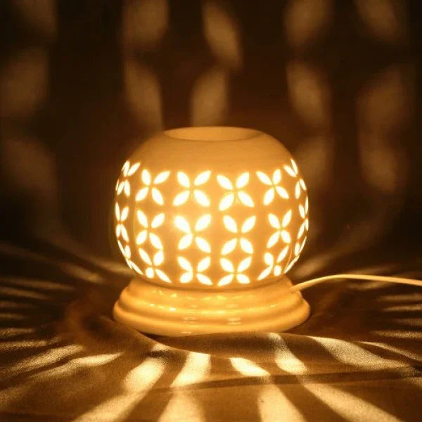 Round electric aroma oil diffuser with floral cut-out pattern glowing in warm light